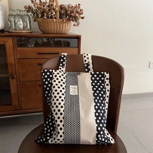 Dettaglio della borsa tote in tela a pois bianchi e neri con motivi geometrici misti