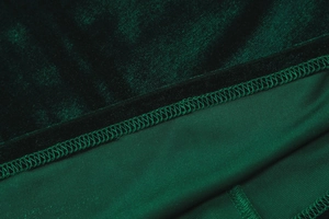 Close-up of deep green velvet fabric texture and professional three-thread overlock stitching