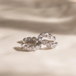 Detailed macro view of silver ear cuffs set with round white zircons on soft fabric