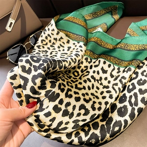 Detail shot of leopard print silk scarf with green stripes and smooth glossy texture