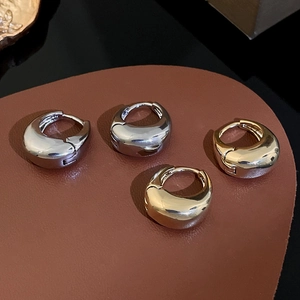 Macro shot of minimalist gold and silver teardrop earrings on a brown leather display