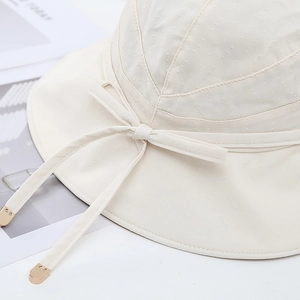 Detail of cream sun hat featuring jacquard fabric with bow and gold metal tips