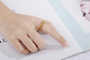 Close-up of a gold-plated croissant ring with a twisted texture on a model's finger