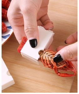 Close-up of manual crayfish peeler tool showing the peeling process on wooden board