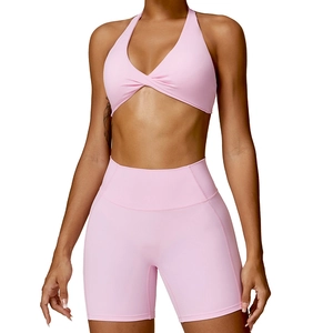 Pink two-piece yoga set with criss-cross halter top and high-waist sports shorts
