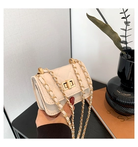 Detail of cream quilted crossbody bag featuring a golden twist lock and chain strap