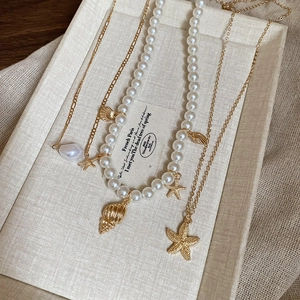 Macro shot of gold starfish and shell pendants on layered pearl necklaces