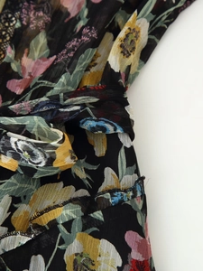 Detailed close-up of floral chiffon fabric texture and waist tie on the black summer dress