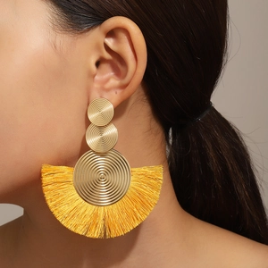 Detailansicht großer Boho-Goldohrringe mit leuchtend gelben Fächerfransen an einem Model