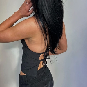 Detail shot of black halter neck top featuring elegant cross-back lace-up tie design