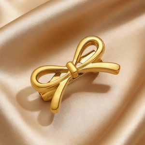 Close-up of a golden ribbon bow hair clip on elegant champagne silk fabric texture