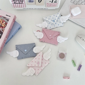 Mini envelope pouch with plush wings and star patterns on a clean desktop setup