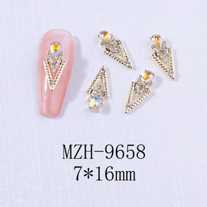 Macro detail of V-shaped gold alloy nail charms with crystals and aurora stones 7x16mm