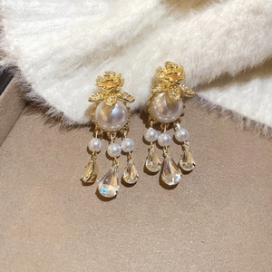 Close-up of vintage golden rose earrings with pearls and crystal droplets on a soft background