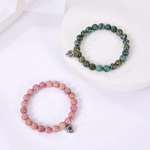 Detailed macro of heart-shaped projection charms on pink and green stone bead bracelets