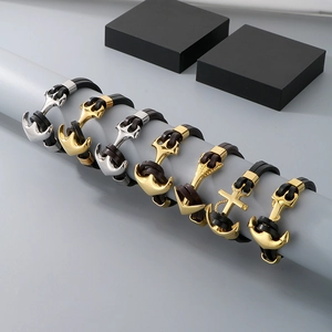 Detail of vintage anchor and cross charms on braided black leather bracelets for men