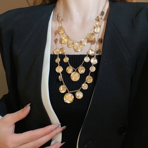 Detail view of multi-layered gold sequin necklaces on a professional black blazer