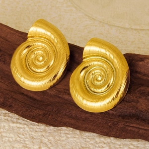 Detailed view of snail shell stud earrings in brushed golden stainless steel on wood