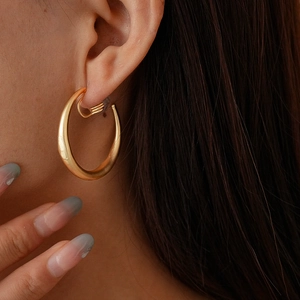 Close-up of minimalist gold geometric round clip-on earrings on a female model