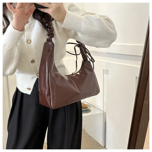Brown half-moon hobo bag with pleated shoulder strap shown on a model for daily style