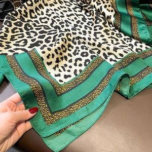 Detail view of leopard print silk scarf with green yellow and black striped borders
