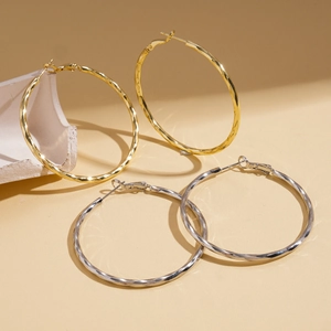 Polished 14k gold and silver plated twisted geometric hoop earrings on a minimalist background
