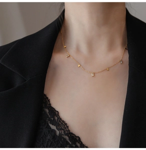 Detail of elegant gold fringe necklace with square crystals on model neck