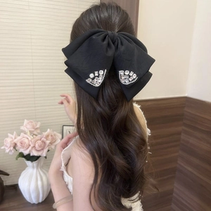 Close-up of black fabric bow hair claw with sparkling rhinestones worn on hair