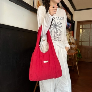 Detail of red quilted tote bag worn by model in a cozy, minimalist indoor lifestyle setting