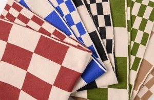Close-up of stacked checkerboard knit scarves in red, blue, black, green, and brown colors
