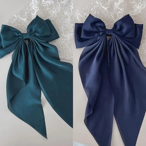 Detailed view of large satin bow hair clips with long ribbons in teal and navy blue colors