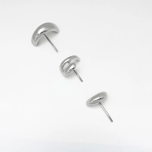 Macro shot of three polished silver metallic stud earrings with liquid drip geometric design