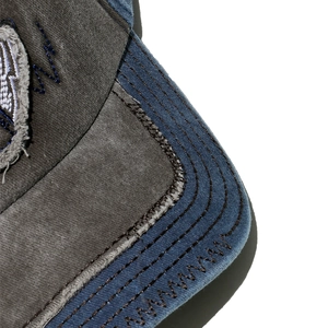 Detailed close-up of distressed brim stitching on retro patchwork denim baseball cap