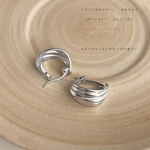 Macro shot of silver layered textured hoop earrings on a decorative tray surface