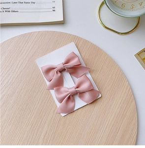 Detail of pink satin bow hair clips for girls set on a vintage aesthetic display