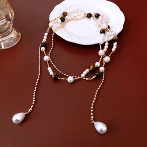 Detail of vintage necklace with pearls, tiger eye beads and golden double chain layers