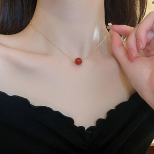 Nahaufnahme einer vergoldeten Halskette mit roter Achatperle getragen von einem Model