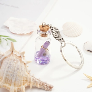 Macro detail of nautical glass bottle keychain with purple sequins and shell charm