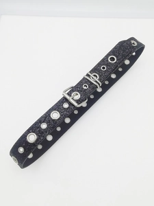 Macro detail of Y2K black glitter belt featuring silver metal grommets and double buckle