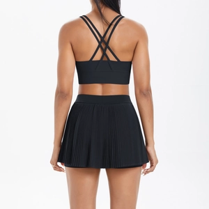 Detail of cross-strap back sports bra and pleated tennis skirt in black athletic set