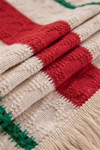 Macro shot of colorful woven cotton linen fabric with red green stripes and tassels