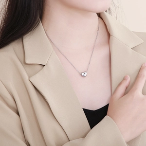 Close-up of a silver heart-shaped stainless steel necklace on a model's neck