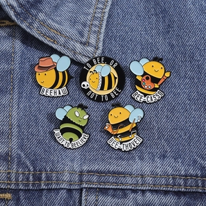 Set di 5 spille ape in smalto con giochi di parole creativi su sfondo denim blu