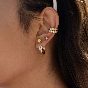 Close-up of a gold-plated stainless steel earring set with white zircon stones on model