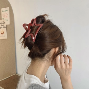 Detailed back view of a burgundy star-shaped hair claw clip on a woman's hair
