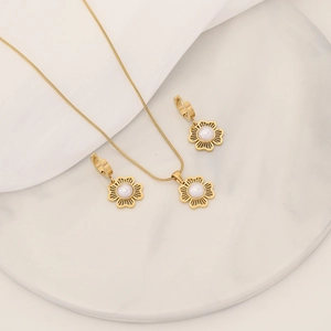 Close-up of golden hollow flower jewelry set with white pearls on a marble tray