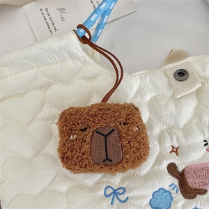 Dettaglio del ciondolo di peluche capibara su una borsa trapuntata a forma di cuore