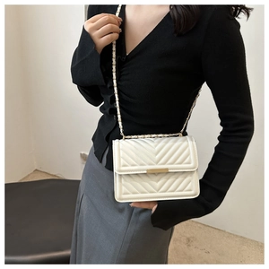 Detailed view of white quilted faux leather crossbody bag with elegant gold chain strap