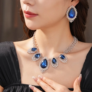 Close-up of diamond-studded necklace and earrings with large pear-shaped blue stones