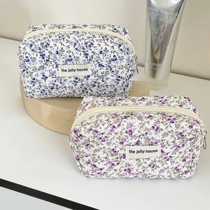 Close-up of floral fabric makeup bags with zippers and woven labels on display blocks